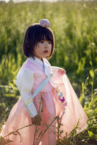 Korean national children pink costume on a four year old girl standing in a field with grass