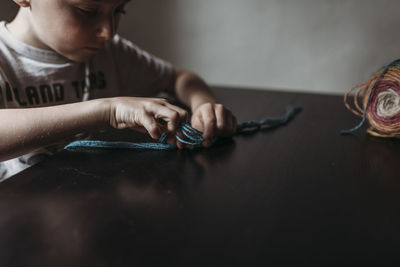 Close up of young boy knitting with fingers at home during isolation