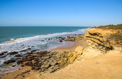 Scenic view of beach against clear blue sky