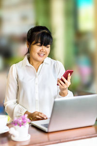 Young woman using phone on table