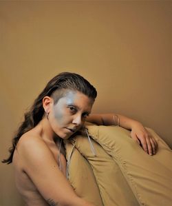 Portrait of shirtless woman against wall at home