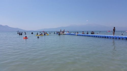 People swimming in sea against clear sky