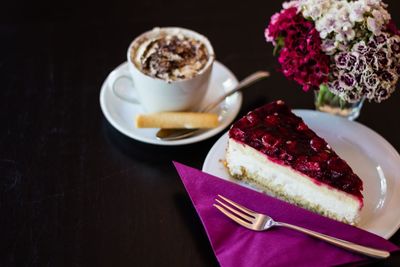 Close-up of raspberry cream cake with cappuccino decorated with flowers