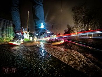 Low section of man with light trails on road at night