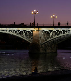 Bridge over river against sky at sunset