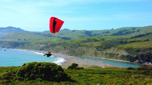 Man paragliding over sea against sky