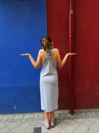 Rear view of girl standing by wall