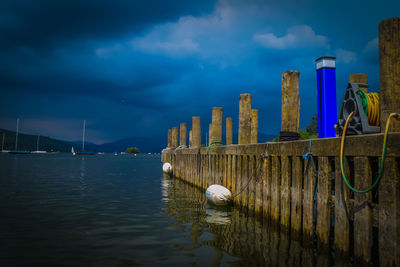 Wooden posts in lake against sky