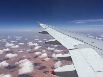 Airplane flying over landscape against blue sky