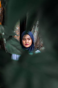 Thoughtful beautiful woman wearing hijab seen through leaves