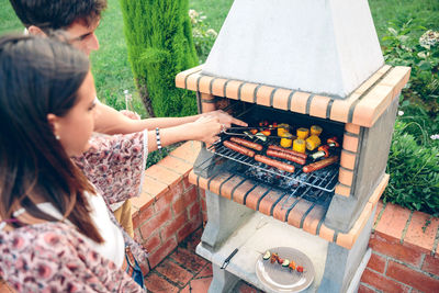 Young couple preparing food on barbecue