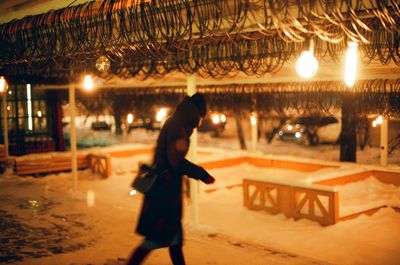 Man walking on illuminated road during winter at night