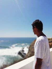 Side view of man looking at sea against sky