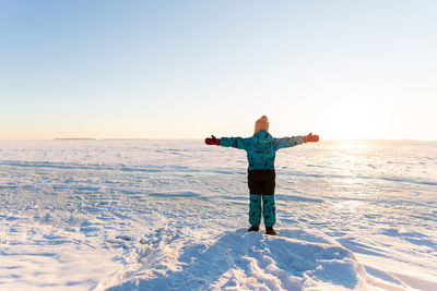 Full length of person standing on snow covered landscape against sky