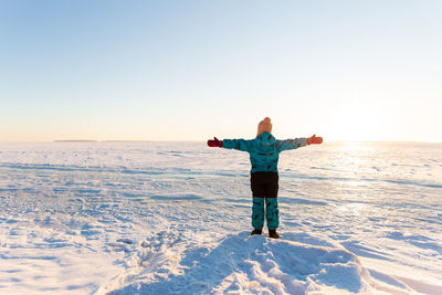 Full length of person standing on snow covered landscape against sky