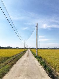 Road amidst field against sky