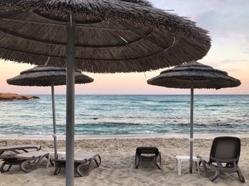 Deck chairs on beach against sky