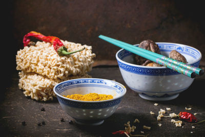 High angle view of raw noodles with turmeric and shiitake mushrooms on table