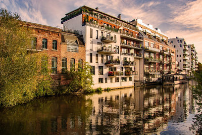 Buildings by river against sky