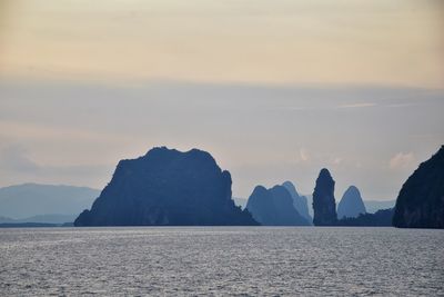 Rocks in sea against sky during sunset