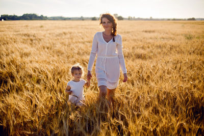 Daughter mother go on the field with ears in the evening in summer.