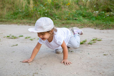 Full length of boy sitting on sand at park