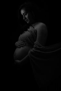 Side view of young woman against black background