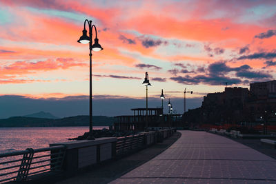 Street amidst buildings against sky during sunset