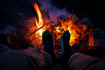 Low section of person sitting by bonfire at night