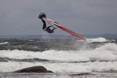 Man windsurfing over sea against sky