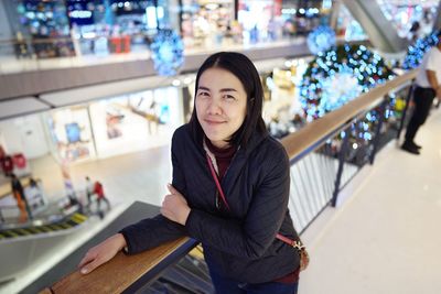 Portrait of young woman sitting on railing