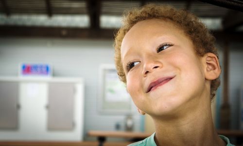 Close-up of smiling boy looking away at home