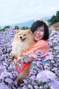 Woman holding a dog in a field of purple flowers