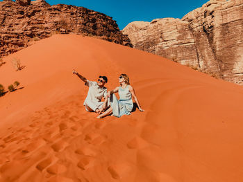People on rock in desert against sky