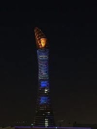 Low angle view of illuminated communications tower against sky at night