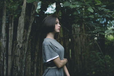 Side view of woman looking away in forest