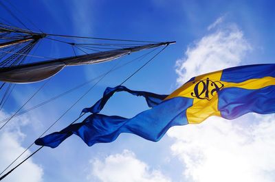 Low angle view of swedish flag waving against blue sky