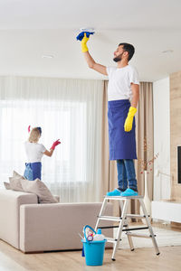 Man with woman standing on sofa at home