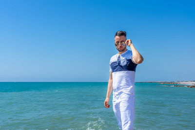 Man standing by sea against clear blue sky