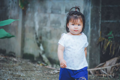 Portrait of cute girl walking against wall