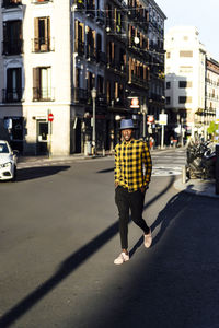 Confident african man with hands in pockets wearing hat while walking in city