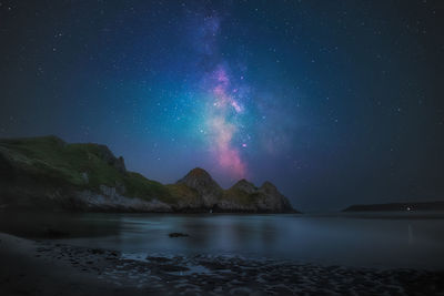 Scenic sea view of milky way on the beach against sky at night