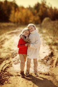 Two sisters in warm sweaters hug and run along the trail in the autumn forest. happy children