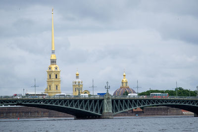 Bridge over river by buildings against sky in city