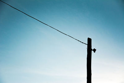 Low angle view of silhouette bird on pole against clear sky