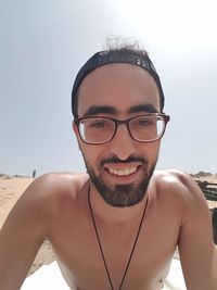 Portrait of young man wearing sunglasses at beach against sky