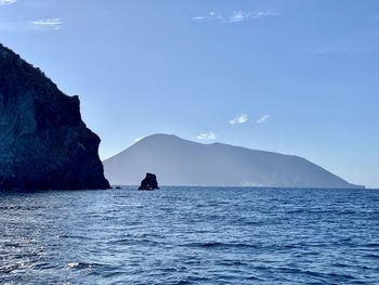 Scenic view of sea and mountains against blue sky