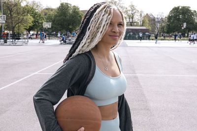 Smiling woman with basketball at sports court