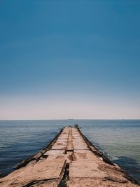 Pier over sea against clear blue sky