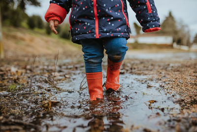 Low section of child standing in puddle